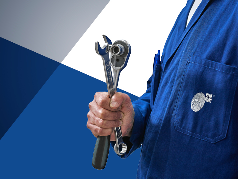 Close-up of man in workshop smock holding two tools in his hand