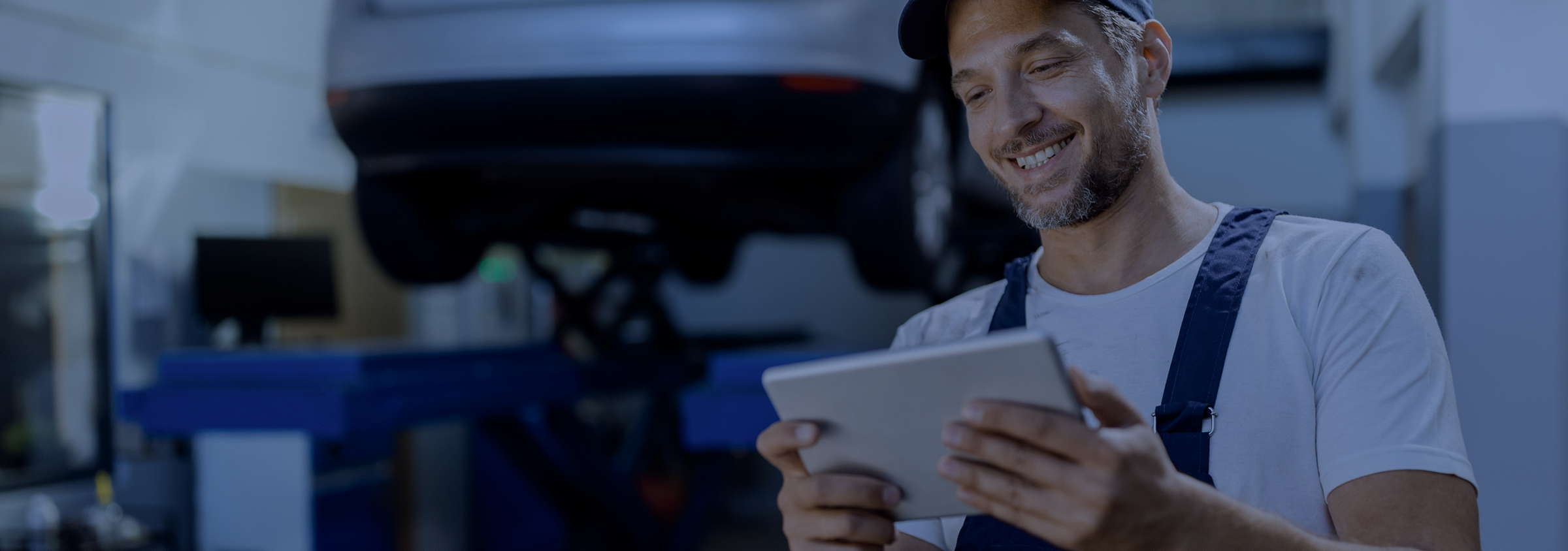 Mecánico sonriente en el taller que se está suscribiendo al newsletter en su tablet